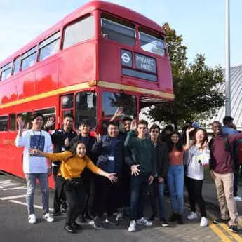 Ƶ students going on a trip and standing in front of a red London bus.